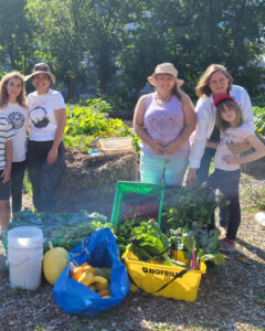 Group of urban farmers in a filed with some of their produce in baskets.