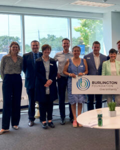 A group of people standing with a sign for the Burlington Foundation.